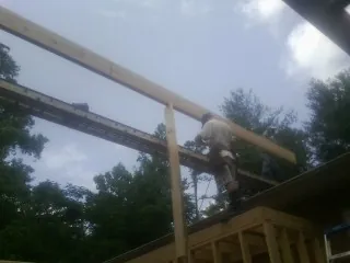 Carpenter setting a ridge beam over a new addition frame — Ice Dam Removal by Roofing Brothers in Wimbledon