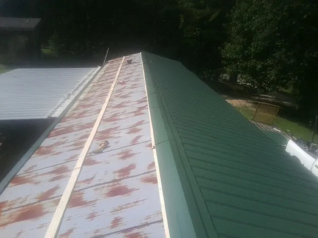 Old rusted panels beside newly installed green metal roofing — Wind Damage Roof Repair by Roofing Brothers in Wimbledon