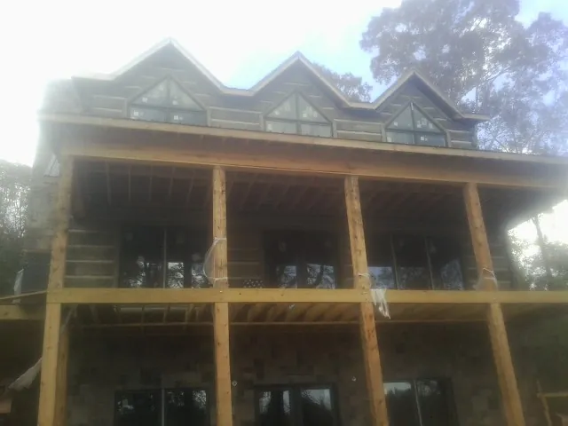 Dormers and porch framing on a large log home under construction — Roof Coating work by our crew in Wimbledon
