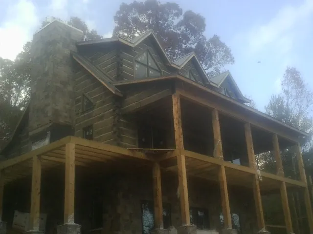 Stone chimney and dormers on a large log home with a timber porch in Wimbledon