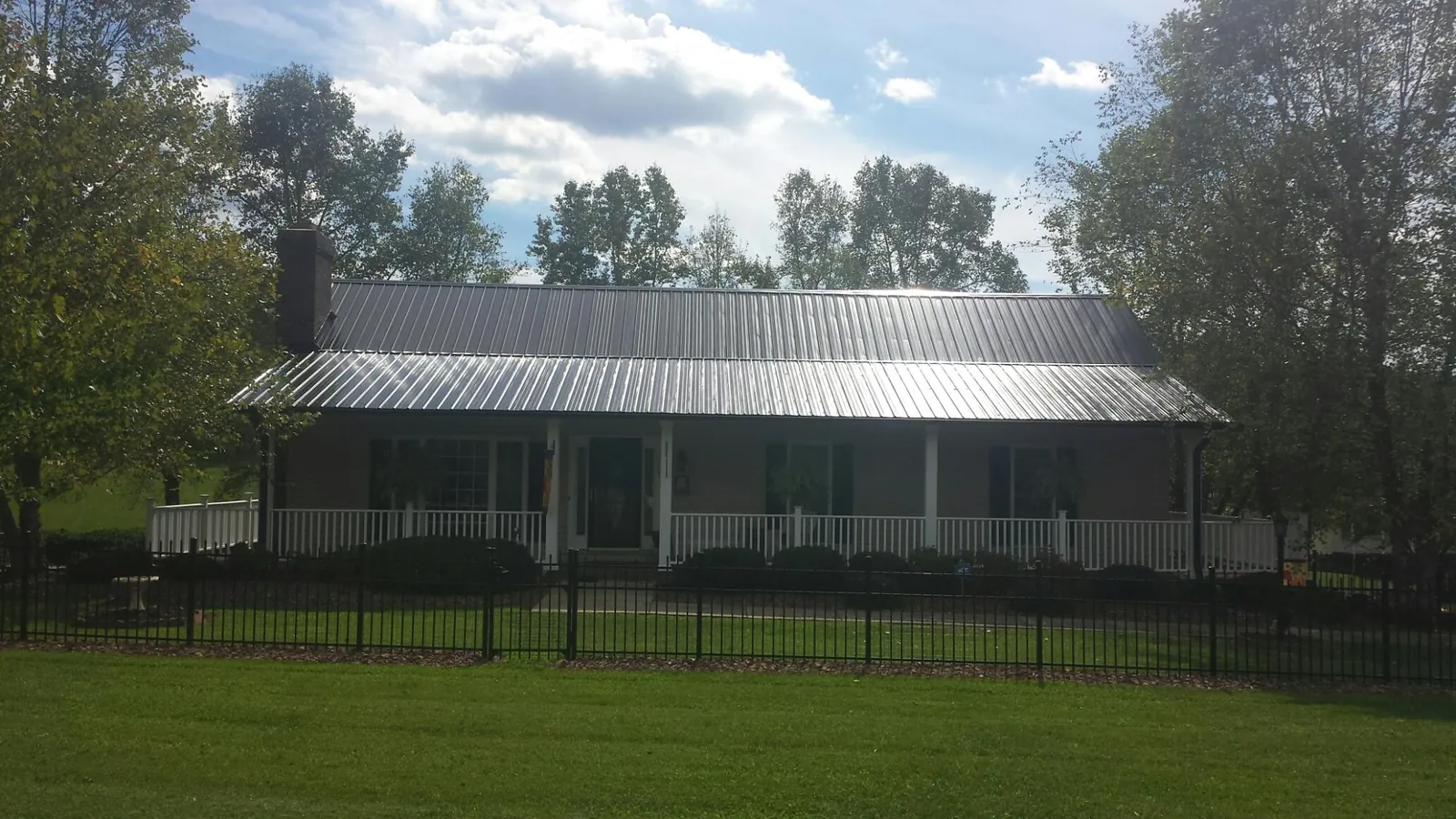 Gray metal roof on a brick ranch with a full width front porch — Gutter Guard Installation work by our crew in Wimbledon