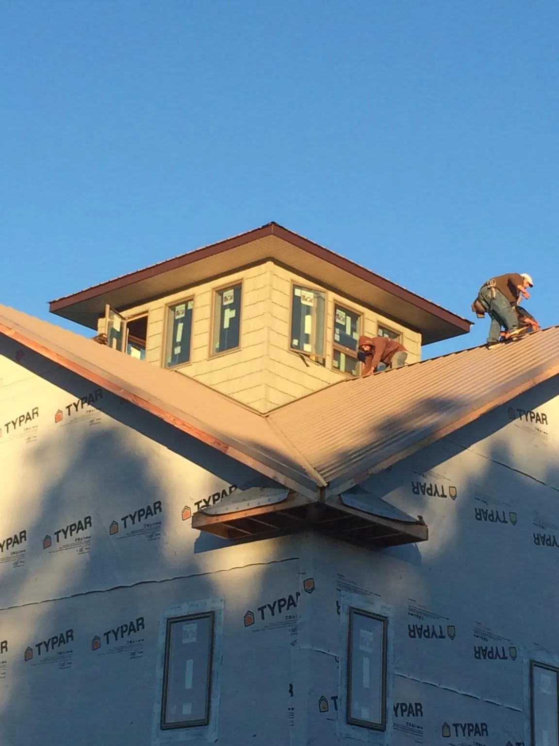 Roofers working around a rooftop cupola on a new metal roof at sunset — Roof Waterproofing in Wimbledon by Roofing Brothers